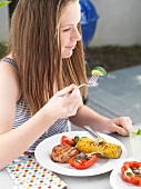 A girl eating a grilled steak with sides