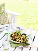 Mixed leaf salad with ham, pears and walnuts on a garden table
