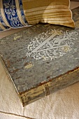 Antiquarian book and vintage cushion on upholstered seat