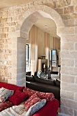 Natursteinwand mit Durchgang im arabischen Stil und gemütlicher Couch mit vielen Zierkissen