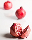 A Pomegranate Cut in Half; Whole Pomegranates in the Background