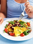 A woman eating a vegetable salad with polenta