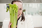 Smiling woman holding head of celery