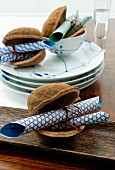 Rolled origami paper in decorative nut shells and crockery with white and blue painted detail on table