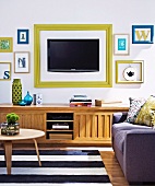 TV and letters in picture frames on wall above traditional wooden sideboard