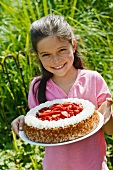 A girl holding a strawberry cake outside