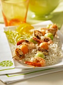 Grilled prawn and scallop kebabs with melon balls on a bed of rice