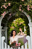 Woman with flowers waving from gate