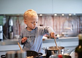 Toddler boy cooking in kitchen