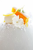 A decoration made with vegetable ice cream, orange zest and a jasmine flower