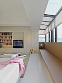 Einbauregal mit integriertem Fernseher in modernem Wohnraum mit erkerartigem Anbau und umlaufendem Fensterband