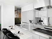 Narrow table with chair in front of a freestanding kitchen counter in a designer kitchen