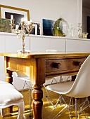 Antique, rustic wooden table with drawer and Bauhaus shell chair in front of half-height sideboard