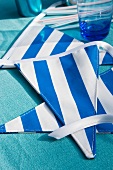 Blue and white striped bunting and drinking glass on blue tablecloth