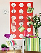 Modern chair at kitchen table with vase of flowers on striped runner against wall with kitchen utensils hanging on wall rack