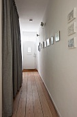 Narrow hallway with wooden floor leading to white front door with window