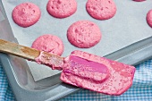 Piles of pink macaroon dough on baking paper