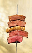Pieces of meat and a sausage on a skewer