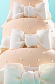A pink wedding cake decorated with white bows