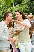 Frau füttert Mann mit Bruschetta bei einem Gartenfest