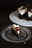 A slice of chocolate cake topped with cream cheese frosting and cherries