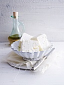 A bowl of feta cheese with olive oil in the background