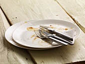A dirty plate with cutlery and a paper napkin