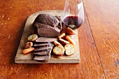 Sliced Buffalo Roast with Carrots and Potatoes on a Cutting Board; Glass of Red Wine