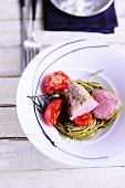 Veal fillet on a bed of noodle with tomatoes