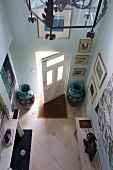 View down into hallway with floor vases, wooden bench and diamond-shaped floor tiles