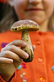 A girl showing a porcini mushroom