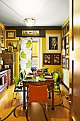 Sunny yellow kitchen with antique dining table, photo portraits on wall and curtain with pattern of gingko leaves