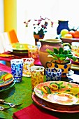Colourful dining table with brightly painted ceramic crockery and patterned glasses