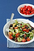 Potato salad with cherry tomatoes, olives, salami, lettuce, onions and basil pesto