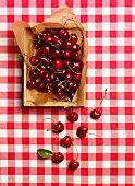 Cherries in a crate on a red and white checked tablecloth