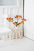 Rhododendron (variety: 'Coccinea speciosa') in vase on floor next to white kitchen table