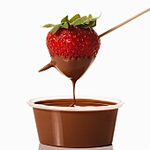 Erdbeere wird in Schälchen mit Schokoladensauce getaucht
