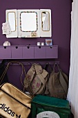 Lila Schubladenregal, Spiegel und Garderobenleiste mit Taschen und Rucksäcken an lia Wand