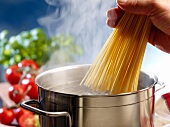 Spaghetti being added to a pot of boiling water