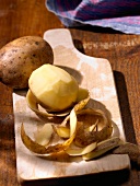 Potatoes, whole and peeled on a wooden board