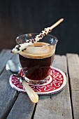A glass of caffè crema with chocolate breadsticks