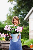 Frau zeigt einen Eimer mit Blumen