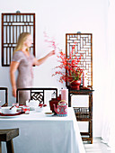 Im chinesischem Stil gedeckter Esstisch; dahinter Stühle und ein Beistelltisch aus Bambusholz