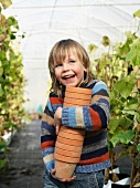 Boy with flower pots in green house