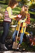 Zwei Frauen mit Spaten & Heidepflanzen im herbstlichen Garten