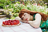 young woman looking at strawberry tart.