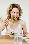 Woman eating mixed salad on table