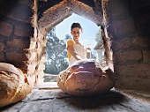 Woman taking bread out of wood oven