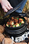 A stew of vegetables and oxtail in a pot over the camp fire