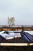 Wooden platform with loungers on a roof terrace with a view across the city